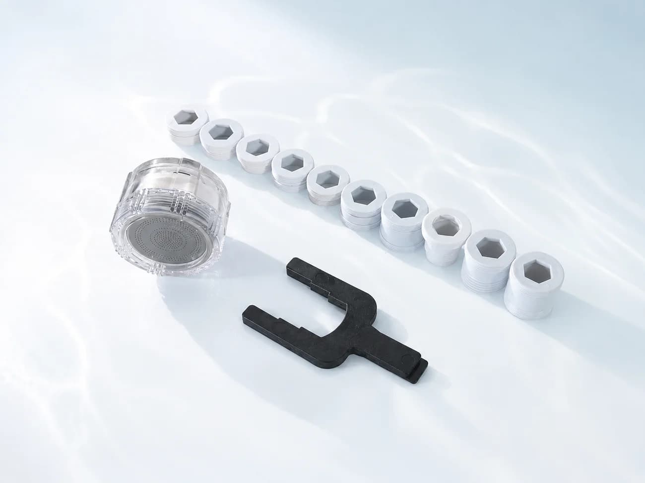 AQUABELL body, faucet adapters and the enclosed spanner laid out on a white surface