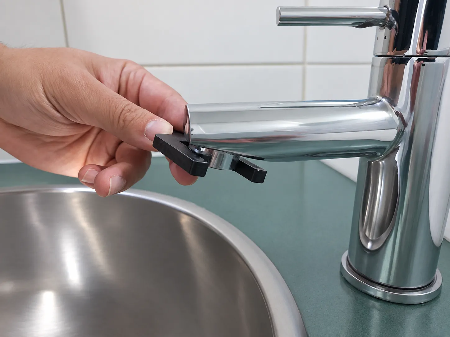 Loosening the aerator at the tip of a faucet with the removal tool