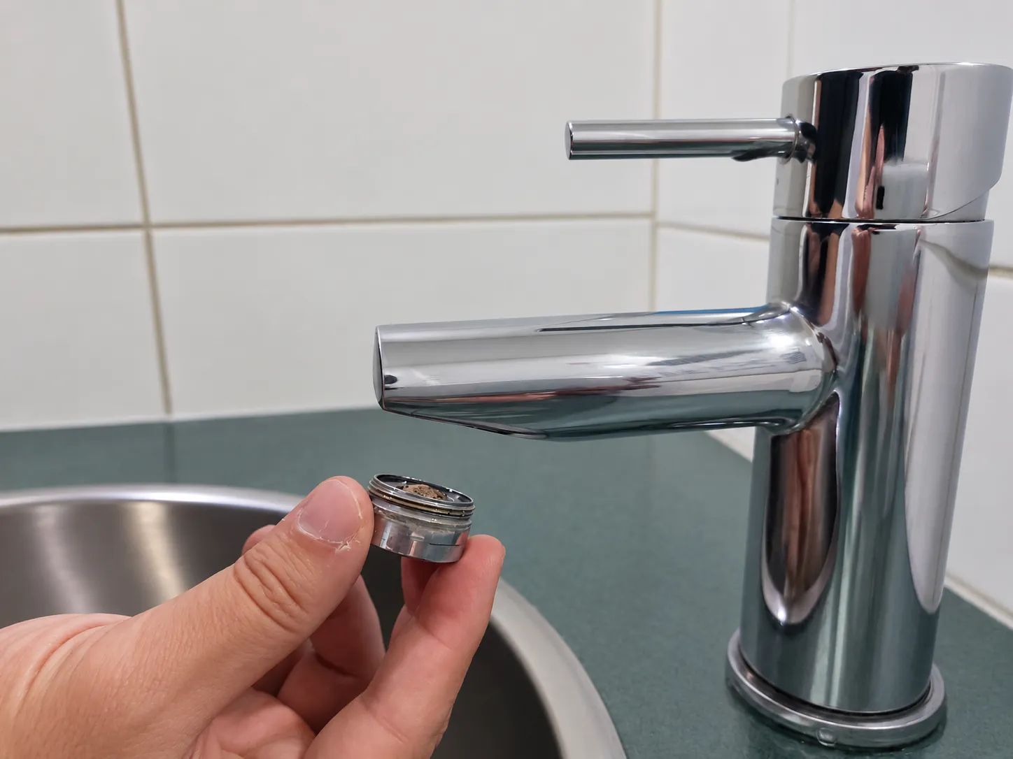 Holding the aerator after unscrewing it from the faucet