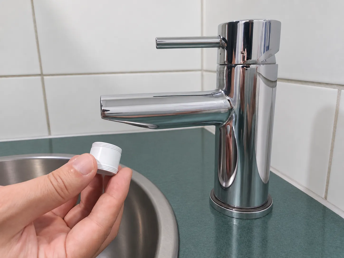 Holding one of the supplied adapters beside the faucet